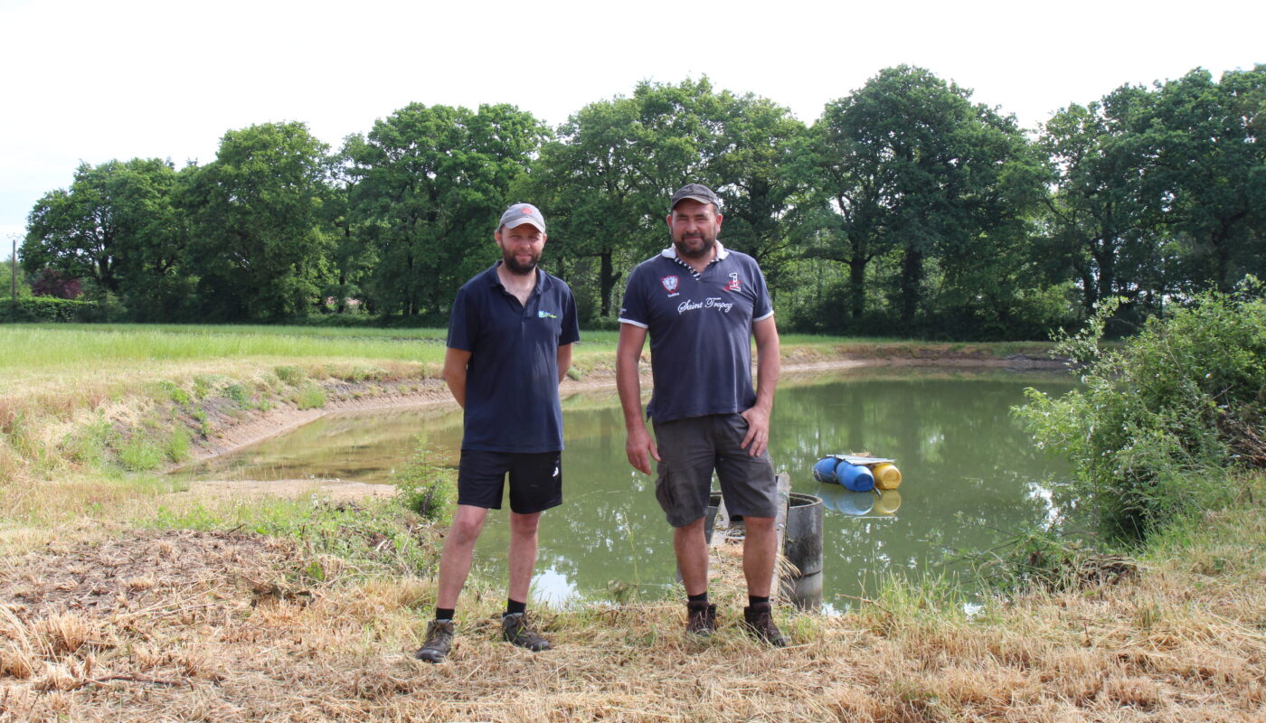 Ludovic Lambert (à gauche) et son frère David devant l’étant de 3000 m3 qu’ils ont fait creuser pour stocker l’eau de pluie récupérée sur les toitures de leurs bâtiments d’élevage.